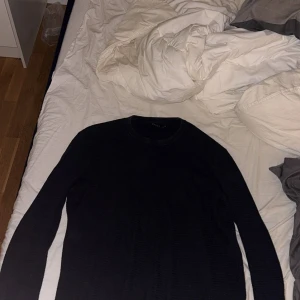 Svart stickad tröja med rund hals - En mörkblå/svart stickad tröja från Riley med rund halsringning och långa ärmar. Enkel och stilren design som passar perfekt till jeans eller chinos. Tröjan har en klassisk passform och är mjuk och skön att bära. Pris går att diskutera vid snabb affär