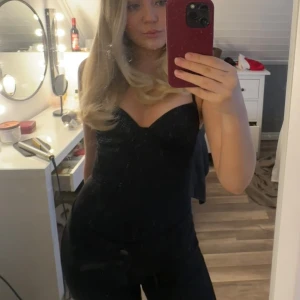 Svart body  - Säljer en väldigt snygg body. Toppen har markerade kupor och en figurnära passform som ger en snygg siluett. Perfekt för dig som vill sticka ut lite extra. 