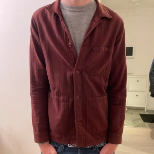 Vinröd overshirt från A Day's March - Tjena! Säljer en vinröd overshirt från A days march . Jackan är i storlek S men kan också passa M. Inga defekter förutom lite färg på lappen inuti jackan. Något man inte ser vid användning. Perfekt för hösten 🪾