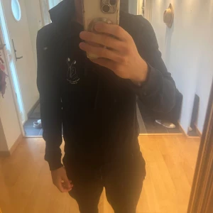 Svart hoodie från Westmark London - Svart hoodie från Westmark London med coolt tryck på bröstet som visar hörlurar och texten 'The only truth is music'. Tröjan har huva med snörning och långa ärmar. Perfekt för dig som gillar musik och vill ha en chill stil.