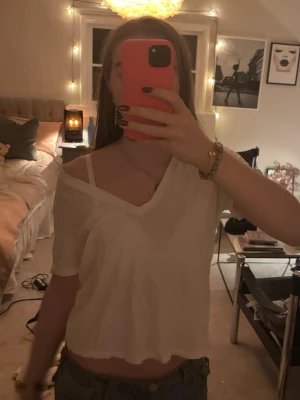 Vit v-ringad t-shirt från Zara - Vit t-shirt från Zara med v-ringning och korta ärmar. Tillverkad i mjuk bomull och har en avslappnad passform. Perfekt basplagg att styla till olika looks.