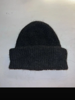 Svart stickad väst från Pieces - Snygg svart stickad väst från Pieces med klassisk rundad form och bred ribbad kant. Västen är tillverkad i ett mjukt och värmande material som passar perfekt för lager-på-lager-stil. Enkel och stilren design som funkar till många olika looks. 