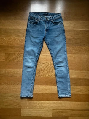 Nudie Jeans, 28/30, Ljusblå, Mycket Bra Skick - Hej! Säljer ett par snygga och klassiska jeans från Nudie Jeans, då de inte kommer till användning längre. Jeansen är gjorda av bomull, använda ett fåtal gånger och i mycket bra skick. Perfekta till både vardag och lite mer uppklätt. Mvh Julius