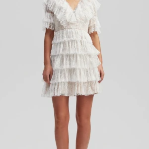 Vit spetsklänning med volanger från By melina - Superfin vit kortklänning i spets med flera lager volanger och v-ringning. Den är från By Melina och är i storlek M. Jag har bara använt den en gång och det var under studenten. Jag älskade den pch är perfekt att springa ut i. Köptes för 2 800kr säljer för 2 000