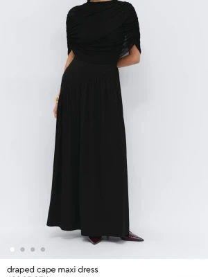 SÖKER Svart draperad cape långklänning  - Söker i storlek L eller XL