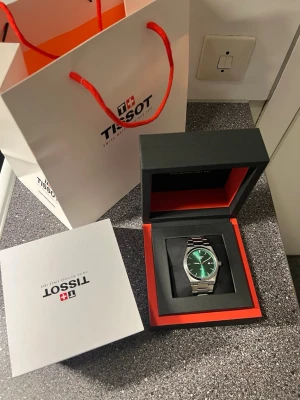 Grön Tissot PRX klocka med stållänk - Snygg Tissot PRX klocka med grön urtavla och stilren silverfärgad länk i rostfritt stål. Klockan har safirglas och klassisk rund form med minimalistisk design. Perfekt accessoar för dig som gillar stilrena detaljer och schweizisk kvalitet.