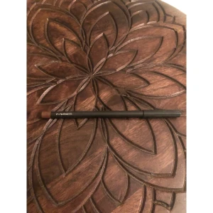 MAC läppenna Cork brun - MAC Lip Pencil i färgen Cork, en snygg brun nyans som passar perfekt för att definiera och forma läpparna. Pennan har en klassisk träform med svart hylsa och korkfärgad spets. Enkel att applicera och ger ett naturligt resultat.