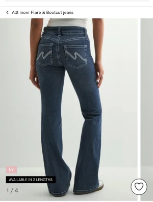 Blå bootcut jeans med broderade fickor - Snygga blå bootcut jeans med vita broderade detaljer på bakfickorna. 