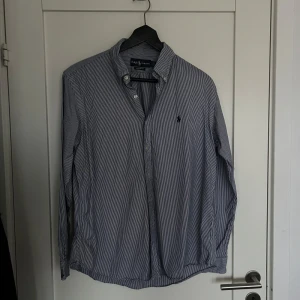 Randig skjorta från Ralph Lauren - Säljer en klassisk blåvit randig skjorta från Ralph Lauren med button down-krage och broderad logga på bröstet. Storlek L men passar även 5