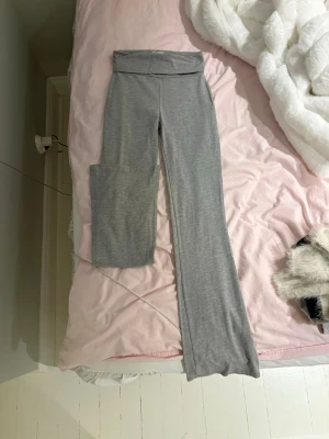 Grå yoga pants - Säljer ett par grå yoga pants med vikbar midja och utsvängda ben. Byxorna är tillverkade i mjukt och stretchigt material.
