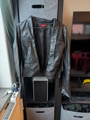 Svart skinnjacka från Sisters Point - Snygg svart skinnjacka från Sisters Point i klassisk modell med långa ärmar och flera fickor framtill. Jackan har en stilren krage och markerad midja för en schysst siluett. Äkta läder