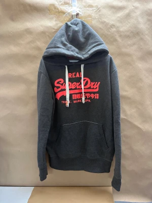 Grå superdry hoodie - Tja den är i mycket bra skick i storlek L. Har ni frågor eller vill ha extra bilder är det bara att kontakta.