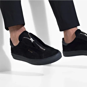 Axel Arigato Clean 90 Zip - Snygga svarta sneakers från Axel Arigato i mocka med rund tå och platt sula. Skorna har en unik dragkedja framtill istället för klassisk snörning. De är använda men väl omhändertagna och i bra skick.