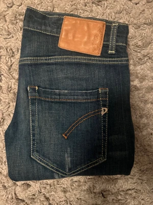 Dondup jeans blå storlek 28 - Snygga blå Dondup jeans i klassisk slim fit med kontrastsömmar och detaljerade bakfickor. Jeansen har normal midja och är tillverkade i slitstarkt denim med coola tvättade effekter. Perfekt för dig som gillar en tidlös och avslappnad stil. 