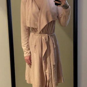 Rosa trenchcoat från Object XS - Säljer en snygg beige trenchcoat från Object i storlek XS. Jackan har långa ärmar, omlottkrage och knyts med bälte i midjan. Materialet är mjukt och lätt, perfekt för vår och höst. Stilren design som ger en chill och clean vibe.