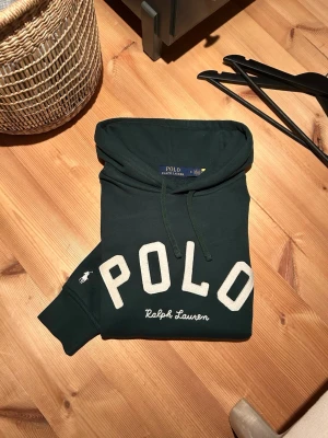 Polo Ralph Lauren Hoodie - En sällsynt grön Polo Ralph Lauren hoodie, i storlek Medium. Finns ett pytte litet slitage uppe vid vänstra axeln, men det är så litet så att man knappt märker av det. Utöver det så är den i extremt bra skick, med inga andra defekter. Den är även äkta, och qr koden funkar. Tveka inte på att höra av dig vid minsta fundering!⭐️Pris kan diskuteras!🤩