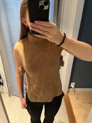 Stickad tröja - En stickad tröja med öppna sidor med knyte som går att dra åt om man vill. I nytt skick 