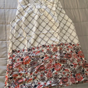 Mönstrad topp - En topp från Soyaconcept i ljusa toner med grafiskt rutmönster upptill och blommigt mönster nertill. Ärmlös modell med rund hals och liten knytning framtill. Materialet känns lätt och svalt, perfekt för varmare dagar.