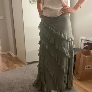 Ljusgrön långkjol med volanger - Supersnygg ljusgrön långkjol med flera lager volanger och små pärldetaljer längs kanterna. Orginalpris är 700kr, endast använd ett par gånger därav priset 