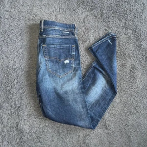 Mörkblå Diesel  jeans med slitningar - Snygga mörkblå jeans från Diesel med coola slitningar och lagade hål på benen. Klassisk femficksmodell med raka ben och kontrastsömmar. Jeansen har en autentisk tvättad look och är tillverkade i slitstarkt denimtyg. W29 L32 slim