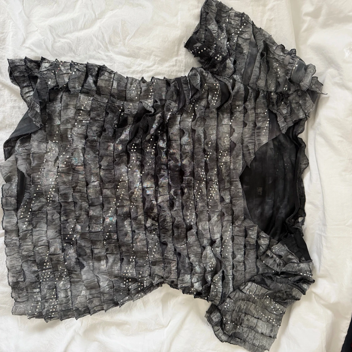 Glittrig svart blus med volangdetaljer