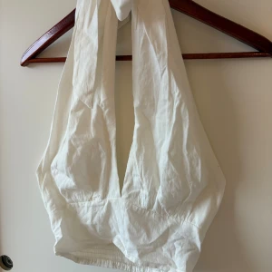 Halterneck tie wrap top  - Supersöt vit halterneck top med smock baktill för extra komfort. Toppen är i ett lätt linnetyg och har en luftig känsla, perfekt för varma dagar. Enkel och stilren design som är lätt att matcha med olika nederdelar. Endast testad aldrig använd 