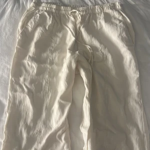 Vita linnebyxor - Snygga vita linnebyxor med elastisk midja och snörning. Byxorna har raka ben och sidofickor.