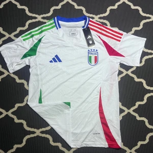 fotbollströja - 👕 Italien Adidas  fotbollströja – Storlek S Snygg och modern landslagströja från Italien i vit färg. Tröjan är helt ny med tag kvar – aldrig använd.  • Broderad FIGC-logga och Adidas-märke • AEROREADY material – lätt & andas bra • Slim fit passform, sitter snyggt • Perfekt till vardag, gym eller match ⚽🔥  Storlek: S   📦 Kan skickas direkt efter köp. 