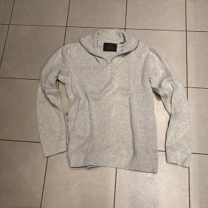 Grå stickad half zip från Jack & Jones - Säljer en stilig grå stickad tröja från Jack & Jones med half zip-dragkedja och hög krage. Perfekt för lager-på-lager och passar till både jeans och chinos. Mjuk och skön känsla, långärmad och i klassisk passform. Använd ett fåtal gånger. Pris kan diskuteras