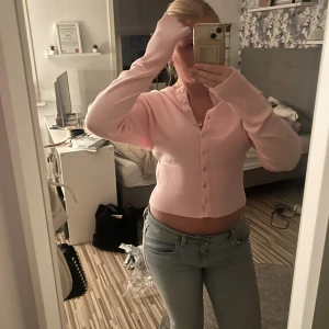 Ljusrosa croppad kofta med knappar - Säljer en superfin ljusrosa croppad kofta med långa ärmar och snygga knappar framtill från Gina Tricot💗Endast använd en gång!