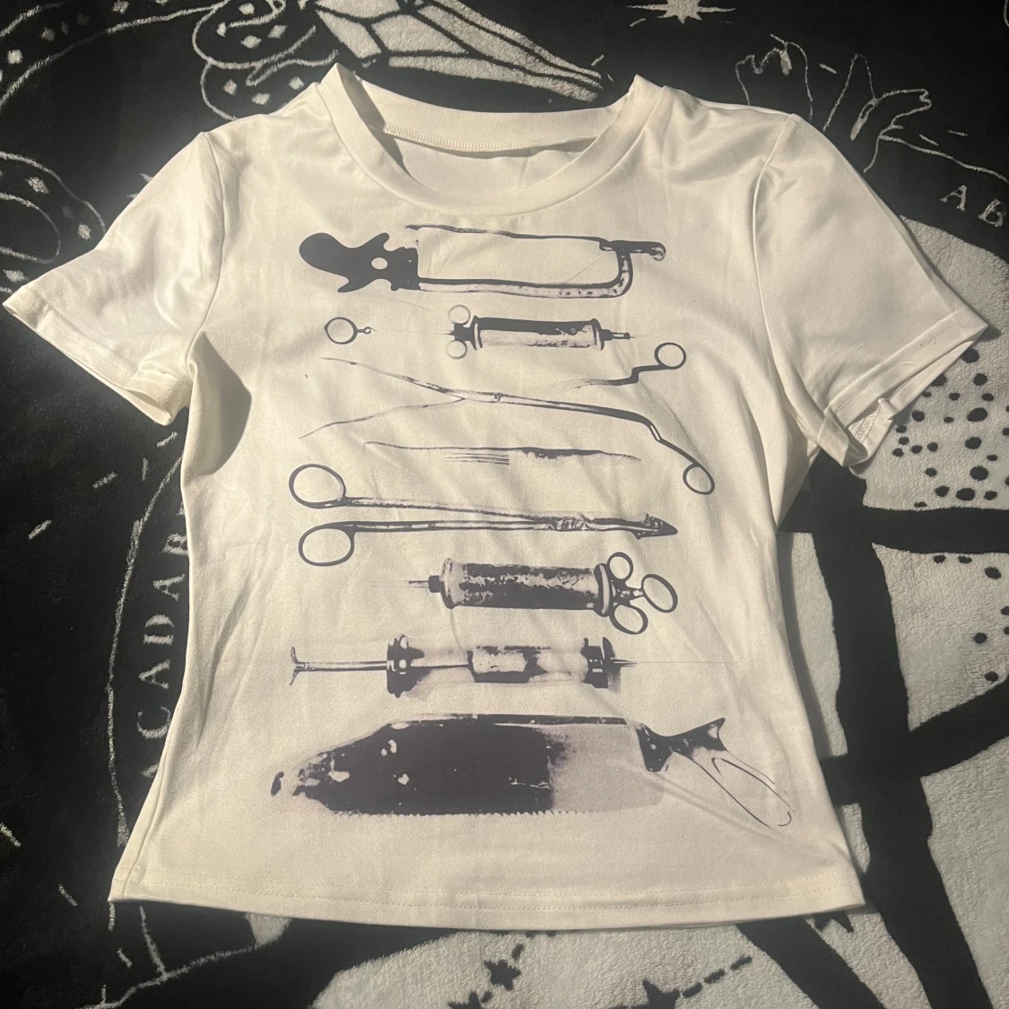 Vit t-shirt med kirurgiska verktyg