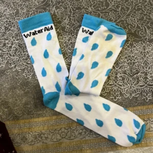WaterAid vita strumpor med blå droppar - Säljer ett par vita strumpor från WaterAid med blå vatten-droppar som mönster. Strumporna har blå tå, häl och mudd, samt svart WaterAid-logga upptill. Aldrig använda, helt nya. Den ena är lite mindre än den andra därav billiga priset