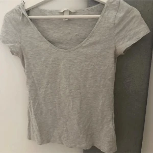 Grå t-shirt från H&M i stl S - Säljer en enkel och stilren grå t-shirt från H&M i storlek S. T-shirten har en figurnära passform och korta ärmar, perfekt för en chill och avslappnad look. Materialet är mjukt och stretchigt bomull som sitter skönt mot kroppen.