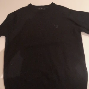 Svart ulltröja från GANT, M - Klassisk svart tröja från GANT i mjuk lammull. Enkel design med rund halsringning och diskret logga på bröstet. Perfekt för lager-på-lager och passar till allt. Långärmad och riktigt skön att ha på sig under kyliga dagar.