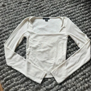 Vit långärmad topp från Amisu - Säljer en stilren vit långärmad topp från Amisu i storlek XS. Toppen har en fyrkantig urringning och är tillverkad i ett mjukt bomullsmaterial. Perfekt att styla med jeans eller kjol för en clean look.