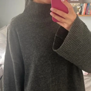 Mörkgrå stickad polotröja - SKRIV FÖR FLER BILDER!!!Mysig mörkgrå stickad polotröja med breda ärmar och hög krage. Perfekt för kyliga dagar och ger en avslappnad, oversized look. Tröjan har en ribbad struktur vid kragen och ärmarna för extra detalj.