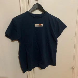 ellesse t-shirt - En mörkblå t-shirt med ett tryck framtill.