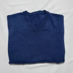 Tröja John Henric - Blå v-ringad tröja från John Henric i 100% bomull. Tröjan har ribbade muddar och mörkare blå förstärkningar på armbågarna. Klassisk och stilren design som funkar till många olika looks. Perfekt för dig som gillar enkelhet med en twist.                     Tveka inte att höra av dig vid minsta fundering!
