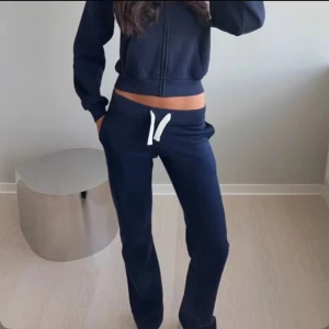 Mörkblå mjukisbyxor med snörning - Snygga mörkblå mjukisbyxor med vit snörning i midjan och raka ben. Perfekta för chill dagar eller när du vill vara bekväm. Byxorna har fickor på sidorna och en avslappnad passform som ger en cool vibe.