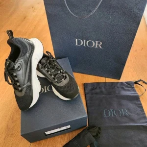 Svarta Dior sneakers herr strl 42 - Säljer ett par svarta Dior sneakers i storlek 42. Skorna har en chunky vit och svart sula, meshdetaljer och partier i skinn. Klassisk snörning och exklusiv känsla, perfekt för dig som gillar lyxiga streetwear-vibbar. Levereras med originalkartong, dustbag och extra skosnören.