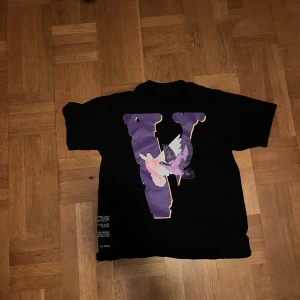VLONE svart t-shirt - Svart t-shirt från VLONE med stort lila V-tryck med duvor på ryggen samt 'Good Intentions' i vitt och lila på bröstet. Klassisk passform och korta ärmar. Perfekt för dig som gillar streetwear och vill sticka ut med en unik design.