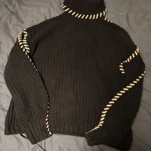 Polotröja  - Säljer en svart stickad polotröja med vita snörningsdetaljer längs kragen och ärmarna. Tröjan har grov ribbstickning och lång ärm och krage. Använd 1-3 gånger köpt på vero moda 