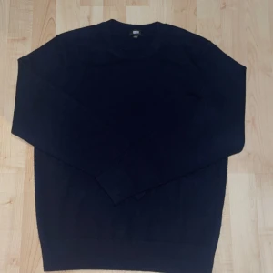 Mörkblå Kashmir tröja från Uniqlo - En stilren mörkblå kashmir tröja från Uniqlo i klassisk modell. Tröjan har rund halsringning och långa ärmar, perfekt för lager-på-lager. Mjuk och bekväm, passar till allt och är enkel att matcha med andra plagg.