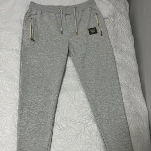 Grå mjukisbyxor med gulddetaljer - Snygga grå mjukisbyxor från M.R väldigt sällsynt att se dessa byxor utomhus. Storleken är S men passar bättre på M. Väldigt sköna mjukisbyxor.