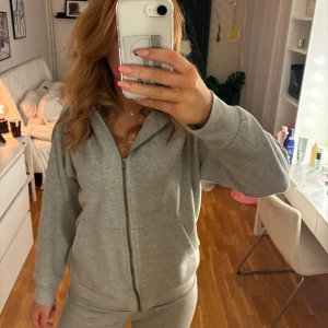 Grå zip hoodie - Mysig grå hoodie från 157 med dragkedja framtill och huva. Tröjan har två fickor på magen och är i mjukt bomullsmaterial, perfekt för chill dagar. Långärmad och enkel att matcha med allt.