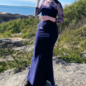 Marinblå långklänning med spetsdetaljer - Vacker balklänning med öppen rygg och mermaid passform. Använts 2 gånger. Köptes när jag gick i 6an, och användes för sista gången sista året på gymnasiet! Passar XS-M (var xs i 6:an, S på gymnasiet, idag M och sitter exakt lika bra som första gången jag bar den).