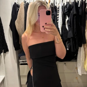 Svart tubtopp med dragkedja - Säljer en stilren svart tubtopp med bandeauform och dragkedjedetalj på sidan. Bra skick!!