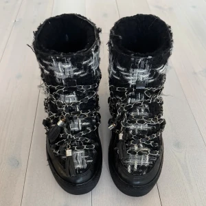 Inuikii vinterskor  - Skor från inuikii med inbyggd kilklack! Använda men har mycket kvar att ge. Vissa ställen på kedjan har missfärgats och blivit lite orange. (En pompom saknas.) Skulle detta vilja åtgärdas kan hela snöret bytas ut. 