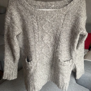 Grå stickad tröja från Kookai - Mysig grå stickad tröja från Kookai med snyggt flätmönster framtill och två praktiska fickor. Tröjan har lång ärm, rund halsringning och ribbade muddar vid ärmslut och nederkant. Perfekt för kyliga dagar och enkel att matcha med jeans eller leggings.funkar även till storlek 40.tror den är oanvänd eller använd 1 gång. Jätte bra skick. Hämtas eller fraktas så fort så möjligt pågrund av flytt. Säljer väldigt mycket gör bra paketpris om du köper flera 