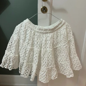 Vit kort kjol med volanger och spets - Supersöt vit kort kjol med broderad spets och volanger. 